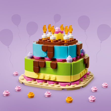 LEGO birthday cake set against a purple background with balloons