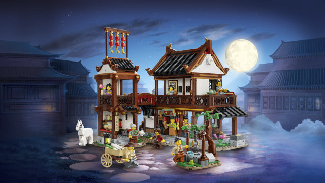 Toy set of a traditional Asian village scene with buildings and characters under a moonlit sky.