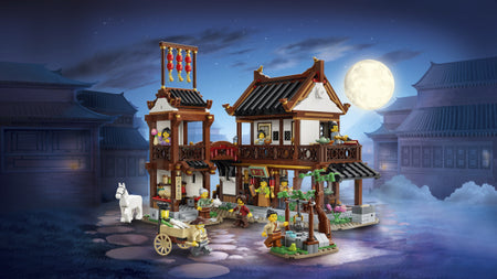 Toy set of a traditional Asian village scene with buildings and characters under a moonlit sky.