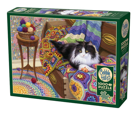 Cobble Hill puzzle box featuring a cat on a colorful rug with yarn and knitting needles.